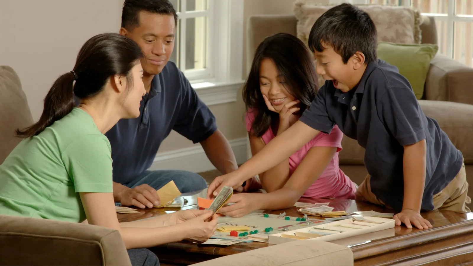 A family laughing as they play a game together at the table