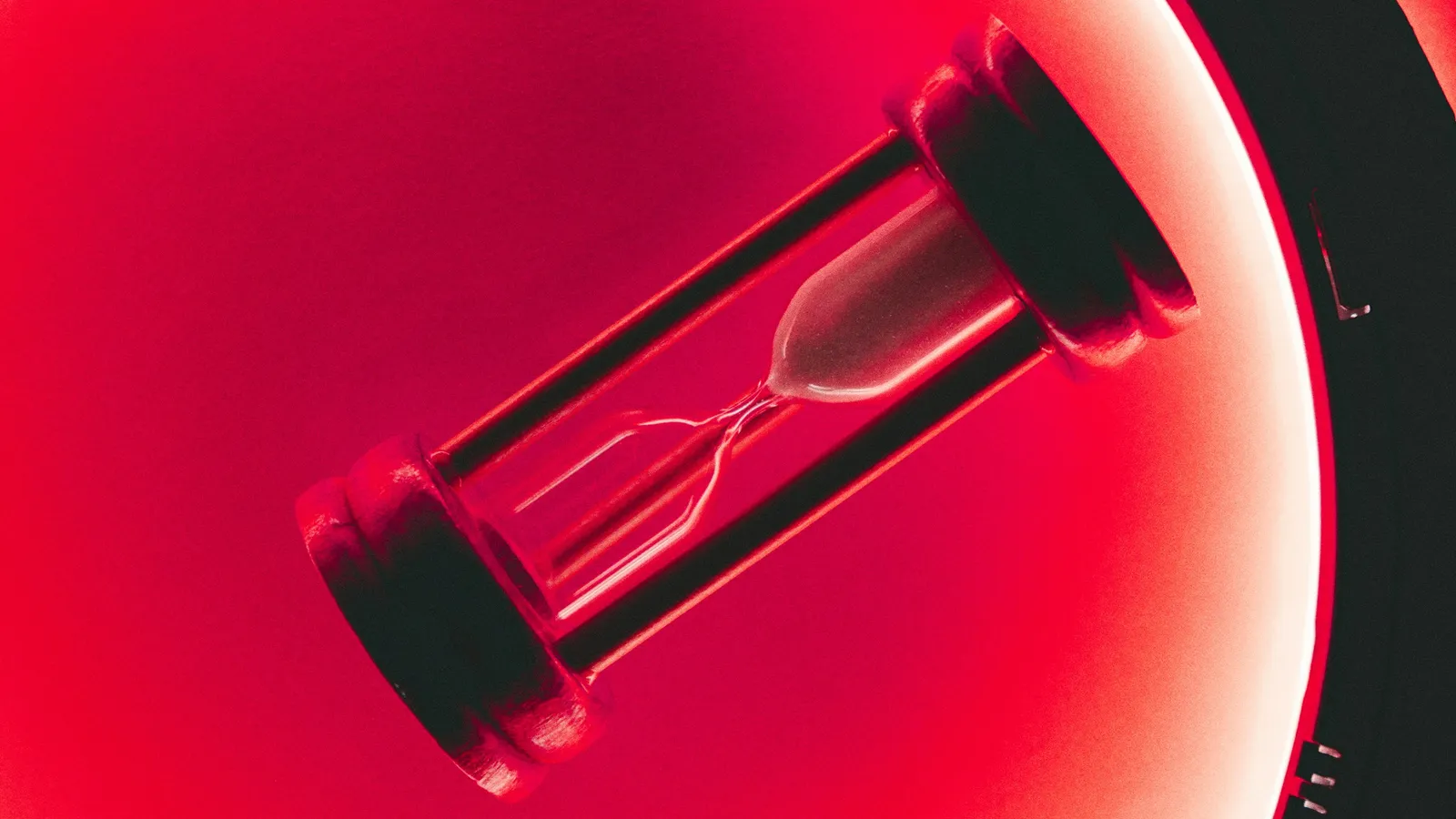 An hourglass glowing red against a red background