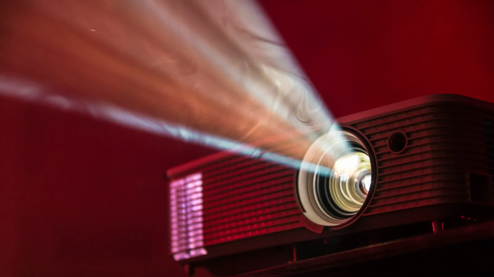 A projector throwing a bright beam of light across a dark red room
