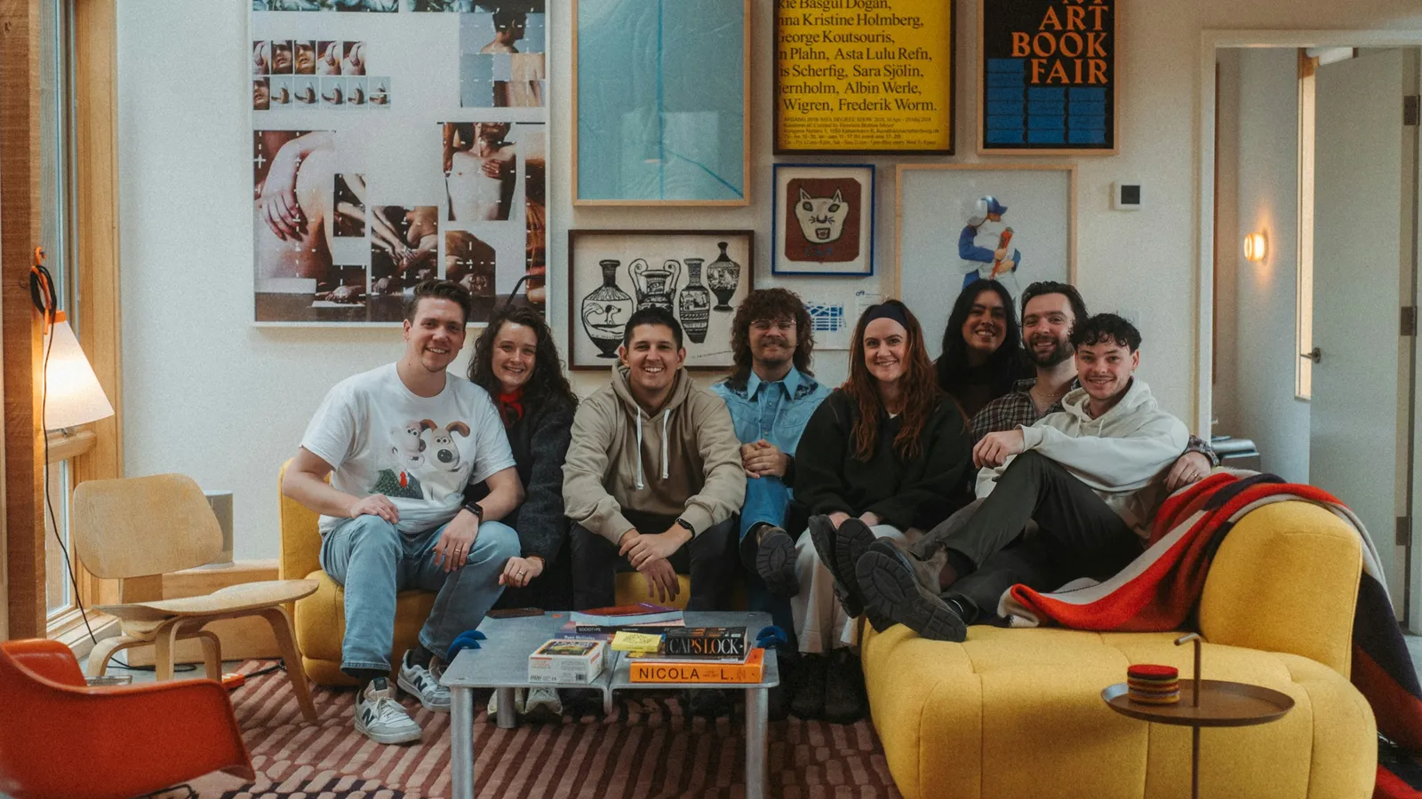 Friends gathered on a yellow sofa in a colourful living room