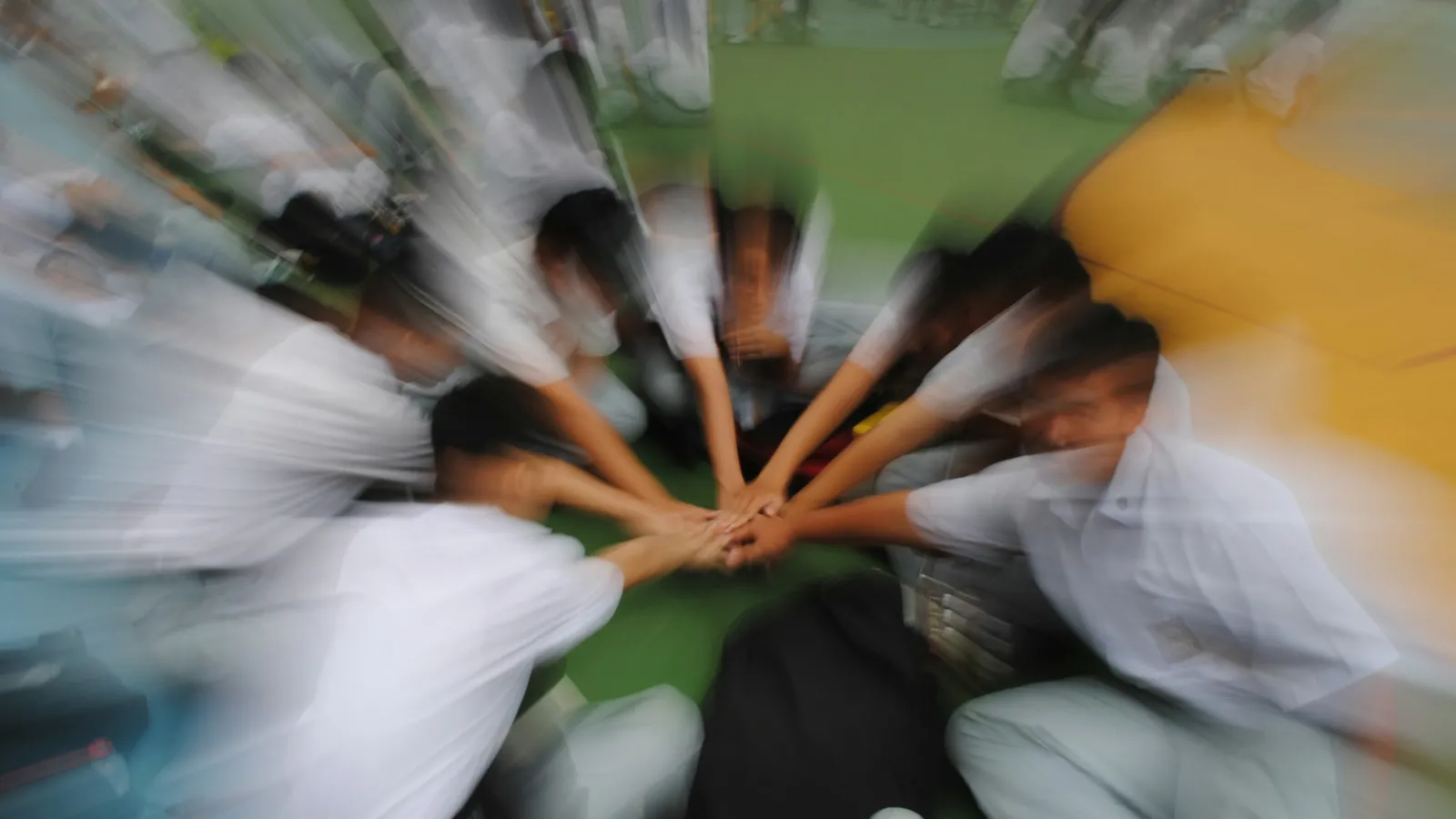 A team putting their hands together in a circle, blurred with movement