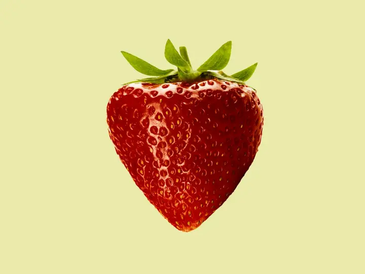 A single strawberry on a pale background
